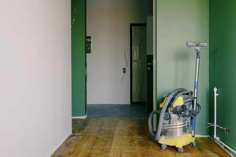 Industrial vacuum cleaner in a renovated room with green walls and wooden floors
